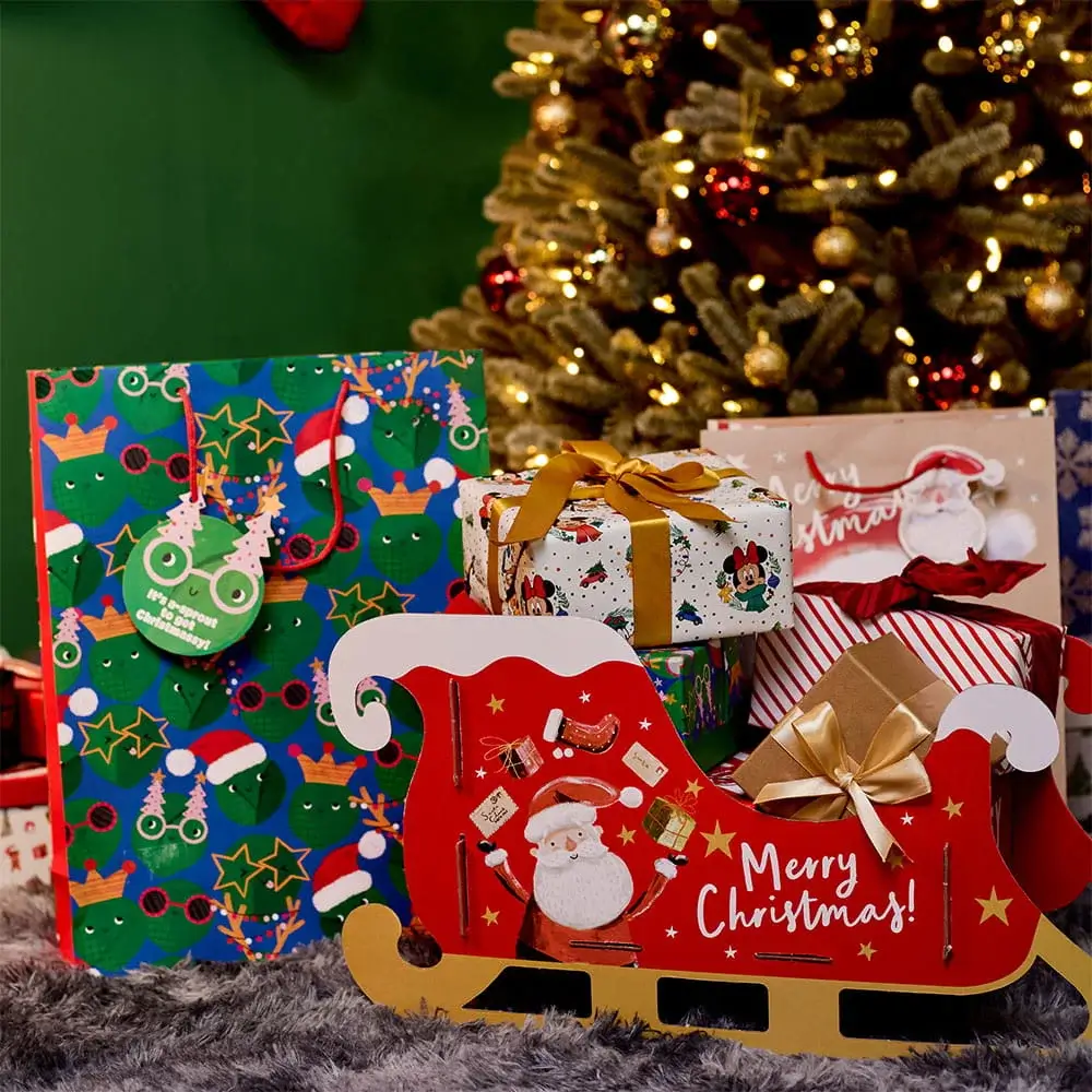 Christmas gift bags, wrapped presents and a festive Santa sleigh gift set displayed in front of a decorated Christmas tree. Christmas gift bags, wrapped presents and a festive Santa sleigh gift set displayed in front of a decorated Christmas tree.